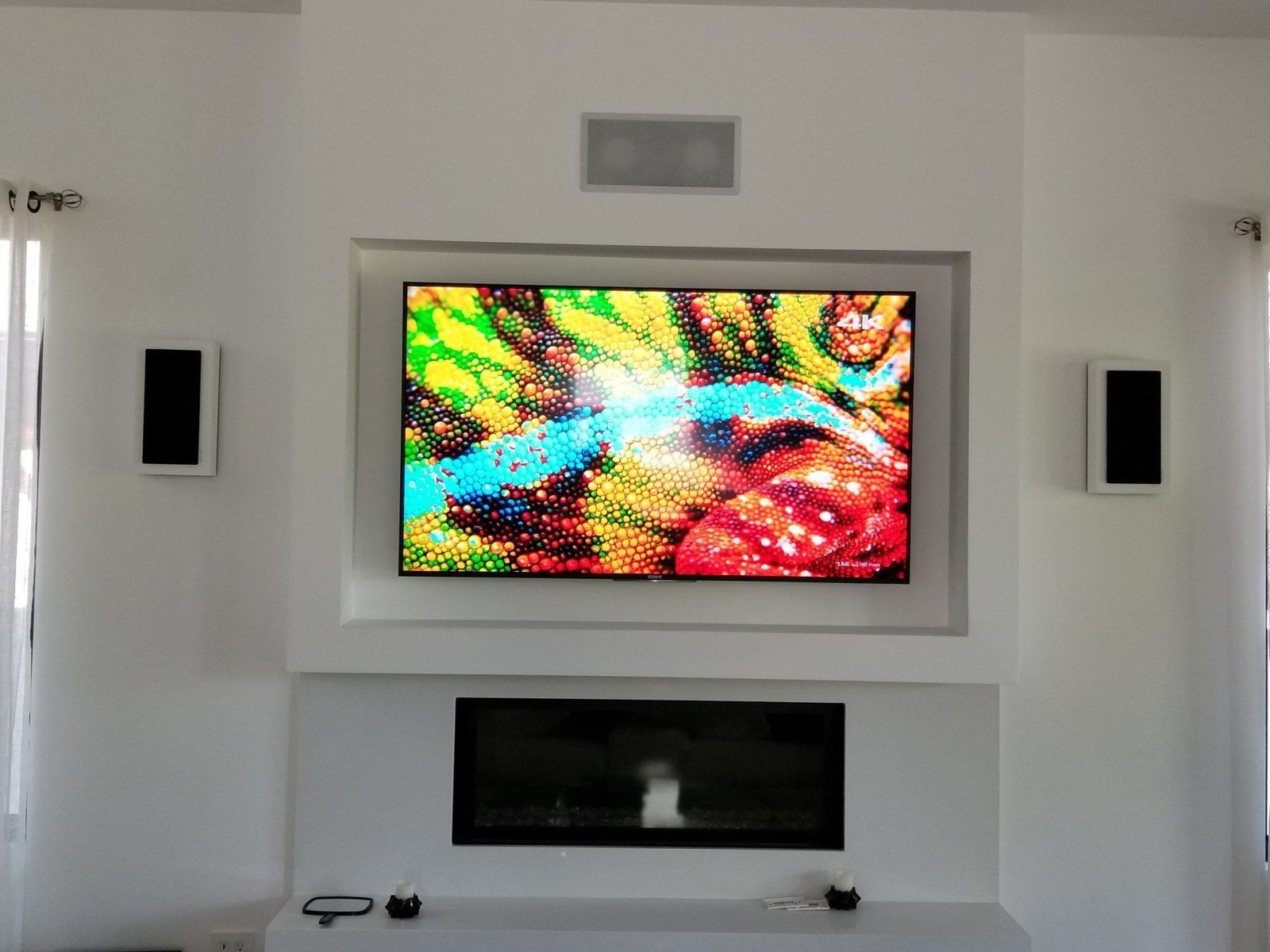 Wall-mounted TV with in-wall speakers over a fireplace by Dr. Gadget